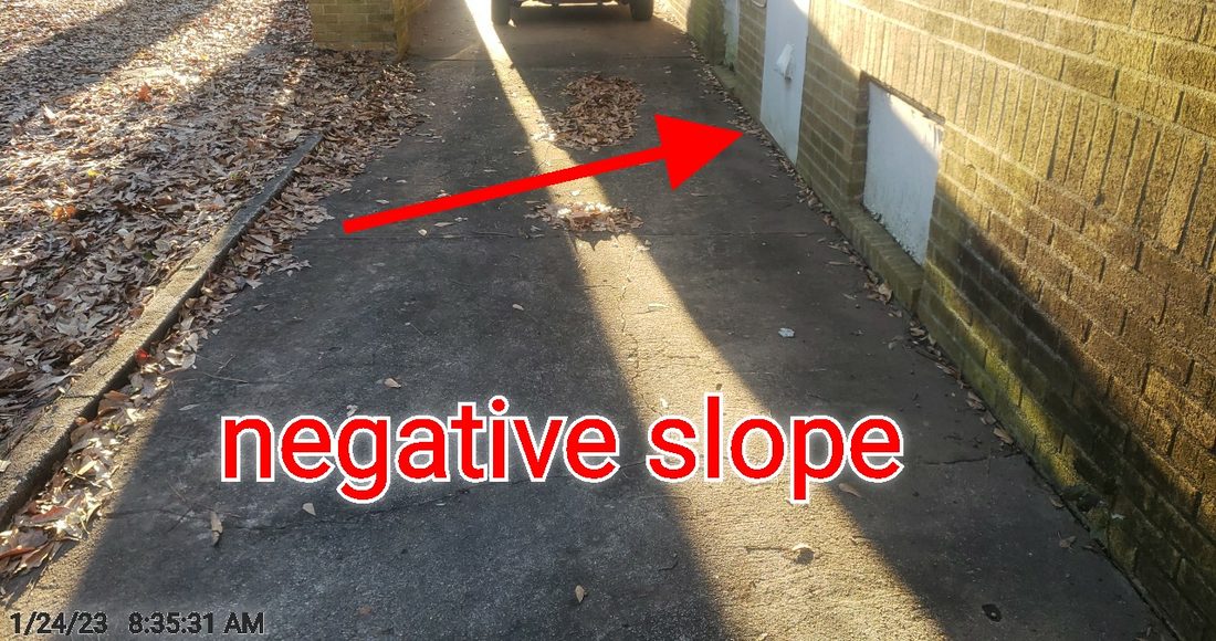 Driveway sloping back toward the house against the foundation (negative grade)